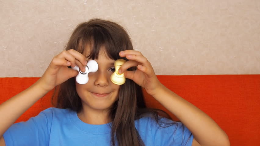 A little girl is spinning two spinners. The child plays with spinners.