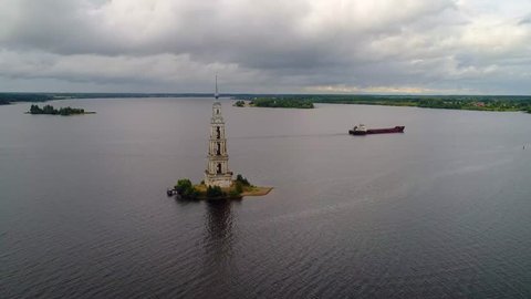 An old abandoned church. Aerial photography of the ancient Russian bell tower, standing on a separate island in the water. Autumn Russian landscape in the city of Kalyazin. A flight over the cross.