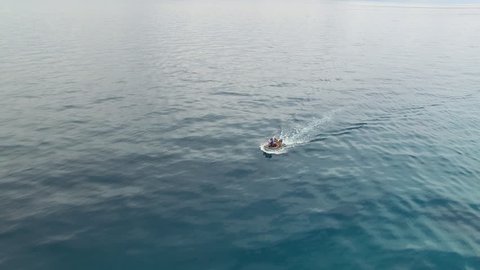 A long shot of a boat on the ocean. Shot moves backward to show a much wider view of the boat on ocean