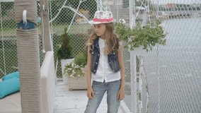 Smart little female model in hat posing and smiling at camera 4K