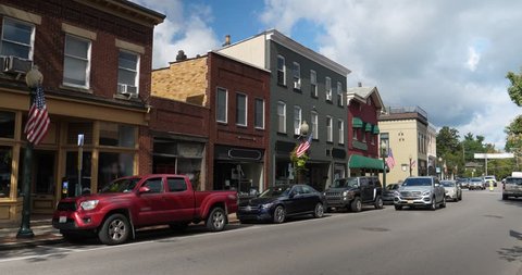A daytime exterior establishing shot of a generic American small town's Main Street shopping district storefronts and traffic.  Winter version available.	