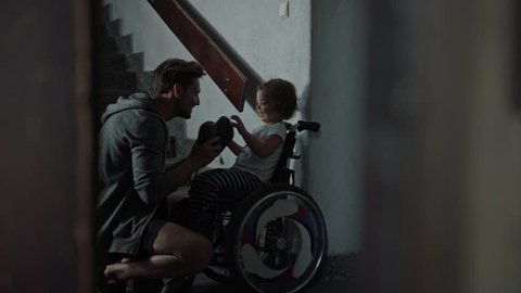 Young father taking care of his disabled child on a wheelchair