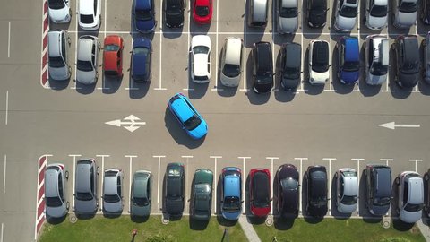 AERIAL TOP DOWN, TIMELAPSE: Bad driver incapable to park a car on parking space in big crowded parking lot. A driver having problems, unable to park a car in parking spot. Parking fail on park space