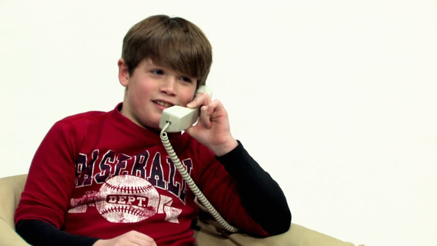 A young boy talks on a telephone.