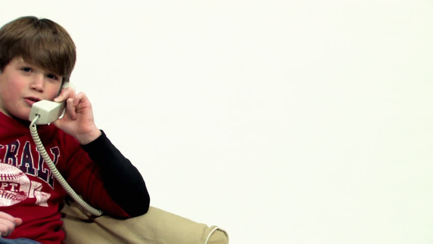 A young boy talks on a telephone.