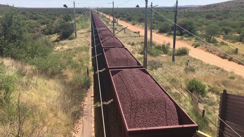 Iron ore being transported on railroad trucks by a very long freight train, South Africa