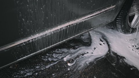 Close up pf man washing his favorite car or van with brush at high pressure self service car wash, uses soap liquid or wax to polish sides of vehicle