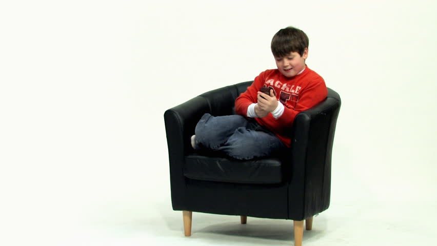 A young boy text messages on a cellphone.