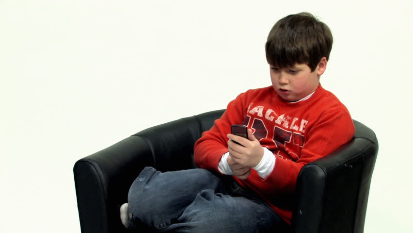 A young boy text messages on a cellphone.