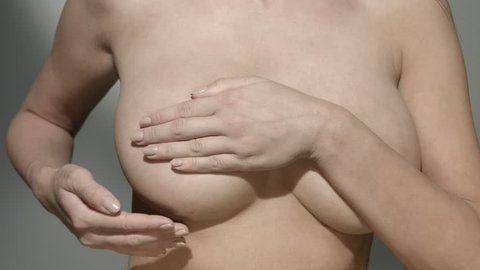 Topless woman examining her breast for cancer signs - slow motion