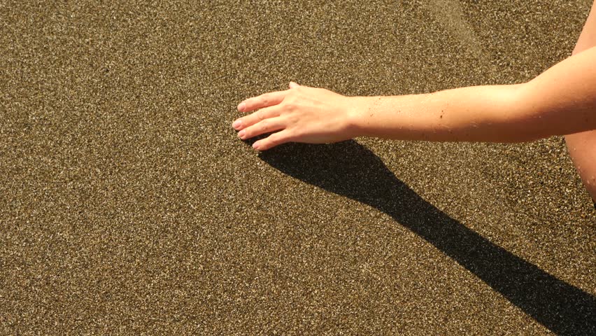 Female hand Drawing the heart on the wet sand. 