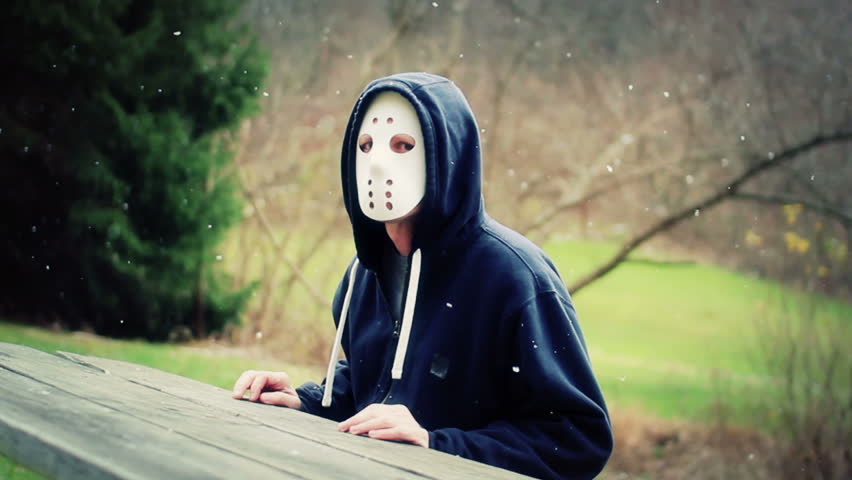 A masked killer sits at a picnic table waiting for a victim.