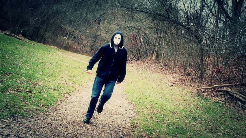 A masked killer happily skips down a wintry forest trail.
