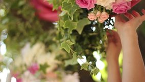 Wedding decor setting. Florists and decorators making rustic floristic decor with pink roses flower compositions with hands. FullHD 1080p footage