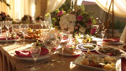 Wedding table rustic style decor with dishes, drinks and flowers in pink and beige colours. Floristic compositions of roses on party banquet dining table.