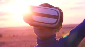 A boy stands in a wheat field at sunset in virtual glasses