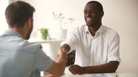 Happy satisfied diverse businessmen making commitment handshaking after successful negotiations, african black entrepreneur shaking hand of new caucasian white partner closing good business deal