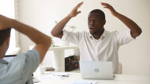 Surprised african-american winner won online looking at laptop in office, excited black businessman amazed by unbelievable luck web offer, good news, raising hands, celebrating success with colleague