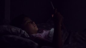 Dolly slide of a nice little girl using her tablet in bed