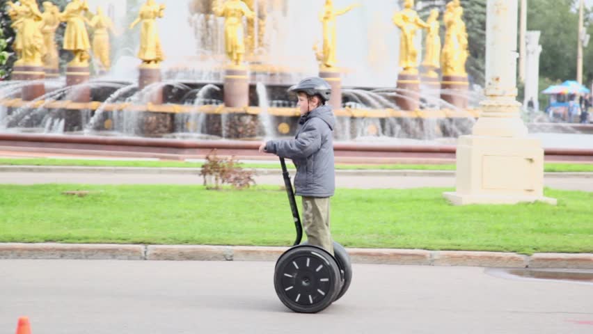 Young boy rides on segway near friendship fountain at VDNH park in Moscow, Russia