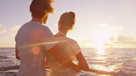 Cruise ship vacation couple enjoying sunset view sailing on small cruise boat at sea. Romantic couple on honeymoon travel at sea looking at sunset. RED EPIC SLOW MOTION.