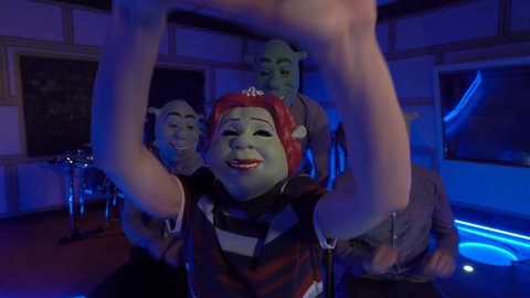 Three Shrek and Fiona claps their hand, sings song, dancing, laughing. People in the masks of shrek have fun with girl