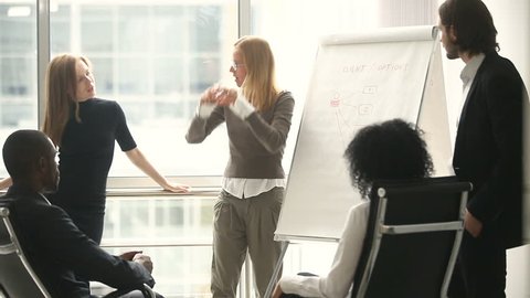 Female manager presents new project plan to colleagues at meeting, explaining ideas on flipchart to coworkers in office, businesswoman gives presentation, discussing ideas with diverse business team