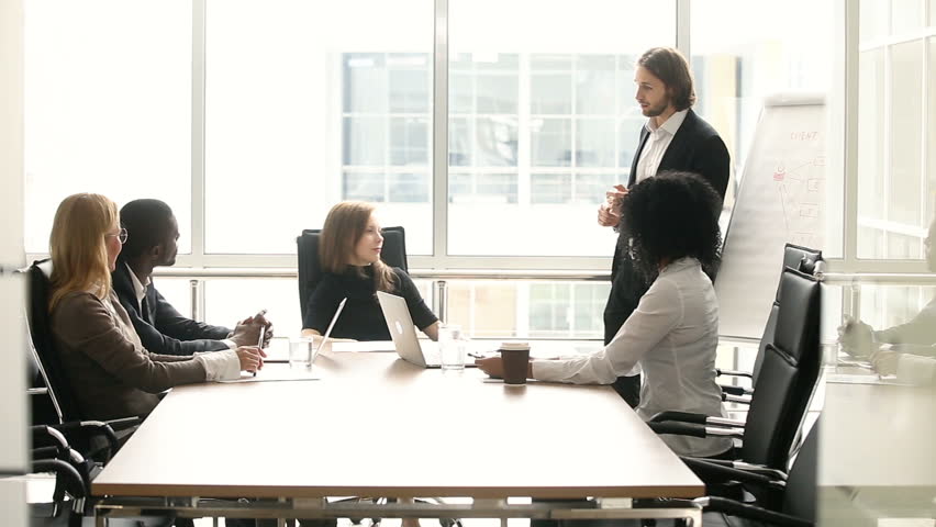 Diverse businesspeople discuss presentation with speaker at meeting, company board asking telling feedback to businessman after making offer, corporate coach answers employees questions in boardroom Royalty-Free Stock Footage #30610966