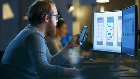 Male Mobile Application Designer Tests New Features on His Smartphone, He Works on a Personal Computer with Two Displays in a Creative Office Space. Shot on RED EPIC-W 8K Helium Cinema Camera. - Powered by Shutterstock - Get 15% off with code: PIKWIZARD15