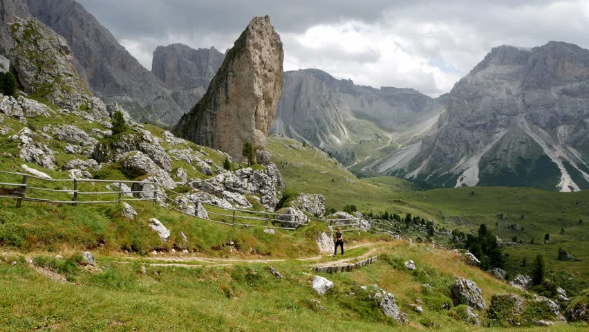 Women makes a hike and goes up the path in a mountainous area. Wide shot