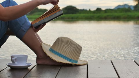 Advertising,Vacation,Time to relax concept - Young Woman reading the book near Lake, Slow Motion. Calm and cozy time in morning and leave space for adding your content.