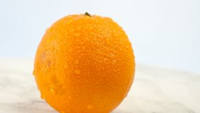 Fresh citrus fruits. Rotate Video footage of the concept of a healthy food and diet. Swirling wet oranges covered with drops on a white marble coating