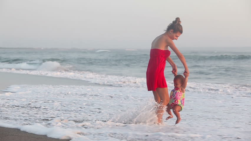 Mother with her daughter having fun on coastline