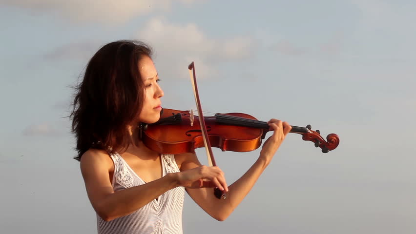 Violinist playing on violin while sunset