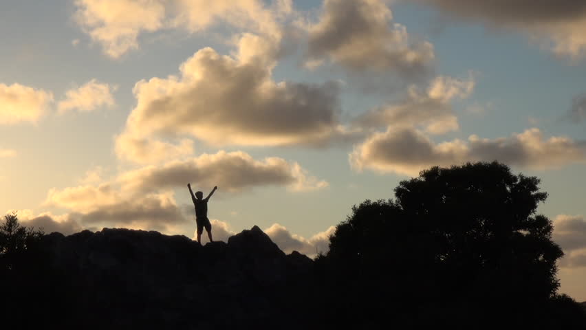 Silhouette of boy with open arms at sunset