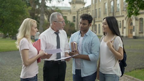 Male teacher giving tests to multi-ethnic students and explaining results