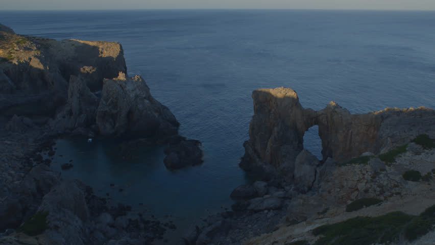 Time Lapse Of Morning Sun Lighting Up Big Rock Formations In Blue Lagoon In Antikythera, Greece. Wide Shot.