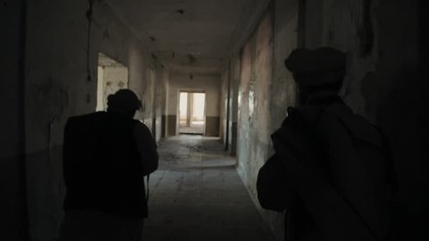 Two armed Mujahideen walk along the corridors of the abandoned building and hunt down the enemy