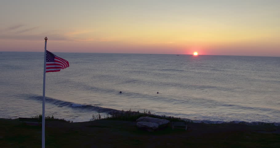 AERIAL: Sunrise, American Flag, and Surfers