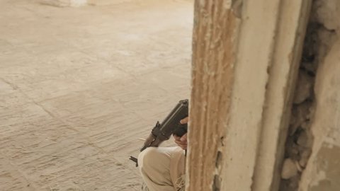Mujahid with firearms aims at the enemy in the corridor of the abandoned building