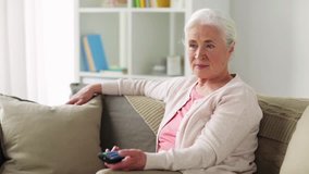 television, retirement and people concept - happy senior woman with remote watching tv at home - Powered by Shutterstock - Get 15% off with code: PIKWIZARD15