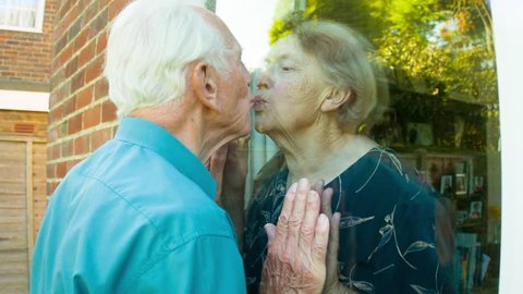 Active retired romantic Senior Caucasian couple kissing through sliding glass doors themes of love romance retired seniors