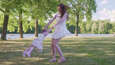 Mom circulates daughter in the park in summer at sunset