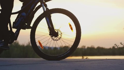 Man on a bycycle on road near lake during beautiful sunset in slow motion. 