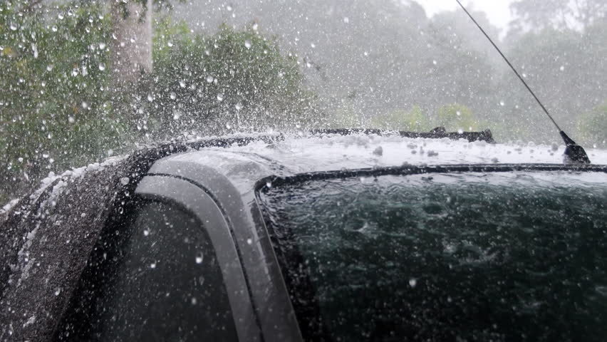 Heavy rain and hail falling on roof of car during violent storm
