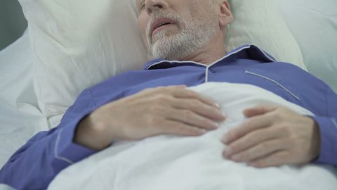 Senior man sleeping in bed and snoring loudly, problems with sleep, apnea