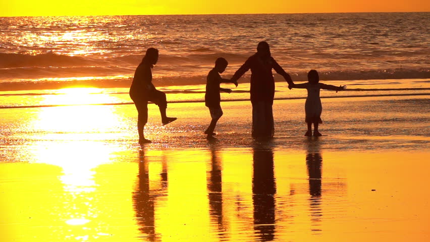 SLOW MOTION, CLOSE UP: Silhouetted Muslim family holding hands standing on dreamy sandy Kuta Beach in Bali watching splashing ocean at golden light sunset. Arab mother and children watching sea waves Royalty-Free Stock Footage #30659947