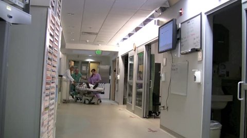 Medical professionals rushing  critical patient through emergency room to surgery.  