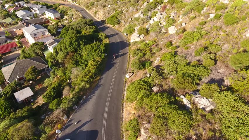 Drone follows motorbike along windy road into Kommetjie in Cape Town