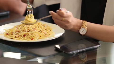 Eating plate of Spaghetti Carbonara and using smartphone